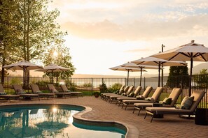 Una piscina al aire libre, sombrillas, sillones reclinables de piscina
