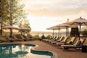 Una piscina al aire libre, sombrillas, sillones reclinables de piscina