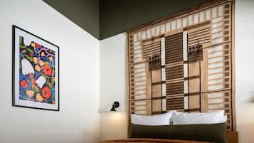 A bedroom with a bed, a wall-mounted light, and a framed floral artwork.