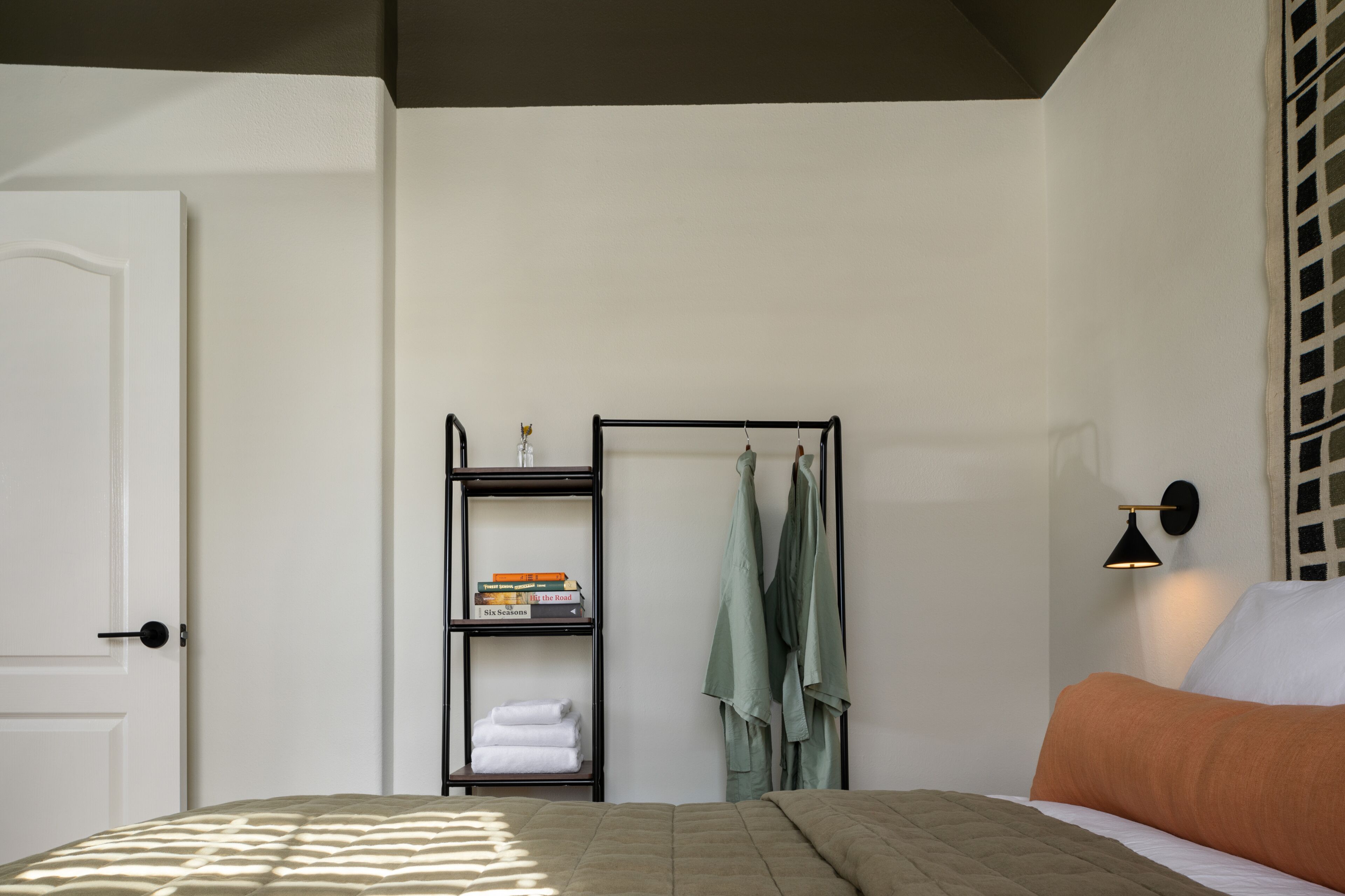 A bedroom with a bed, a wardrobe, and a shelf with books.