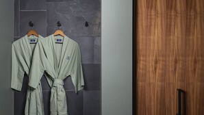 A bathroom with two robes hanging on a rack, a wooden door, and a tiled wall. - Hotel Marina Riviera (Big Bear Lake)