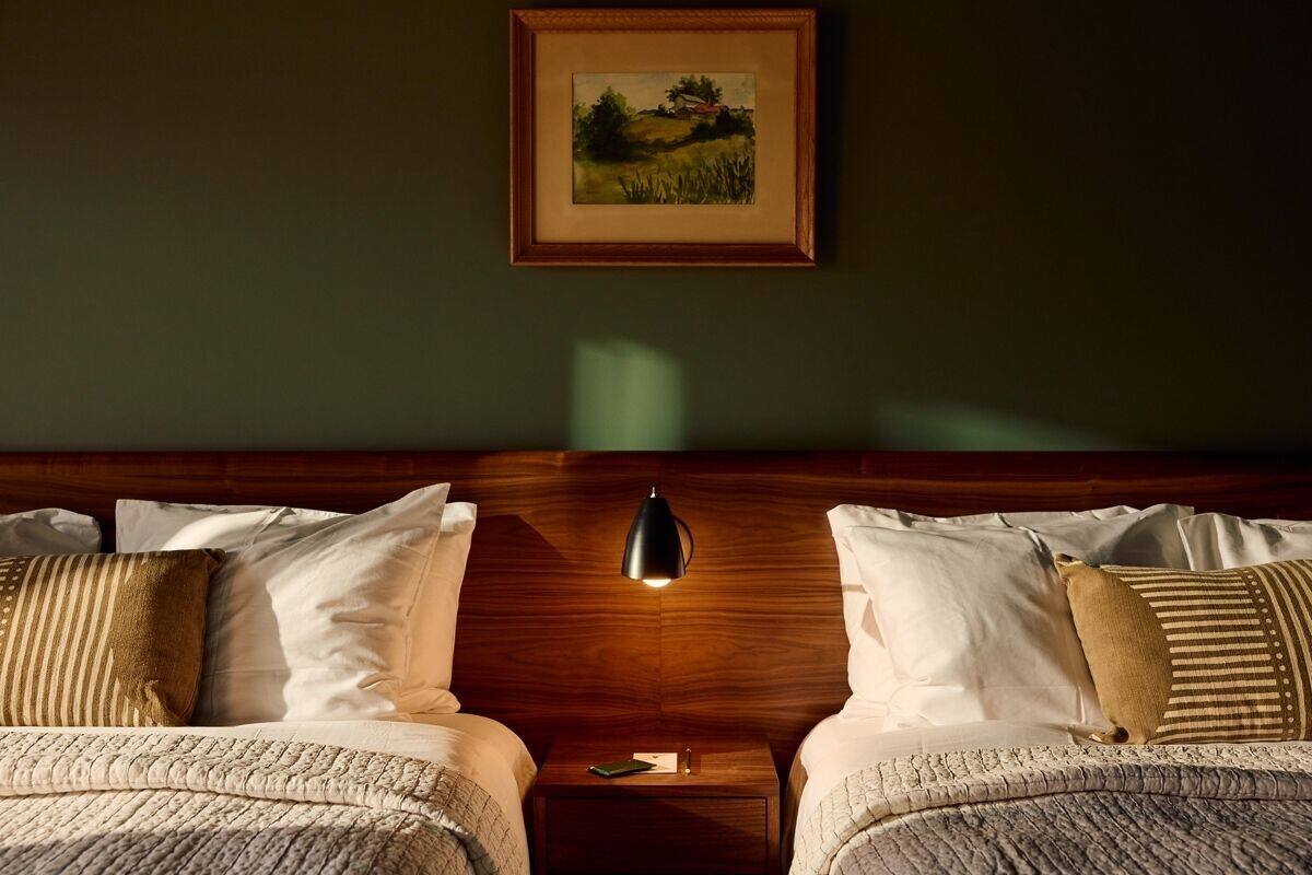 A double bed with a wooden headboard, two bedside tables, and a framed landscape painting on the wall.