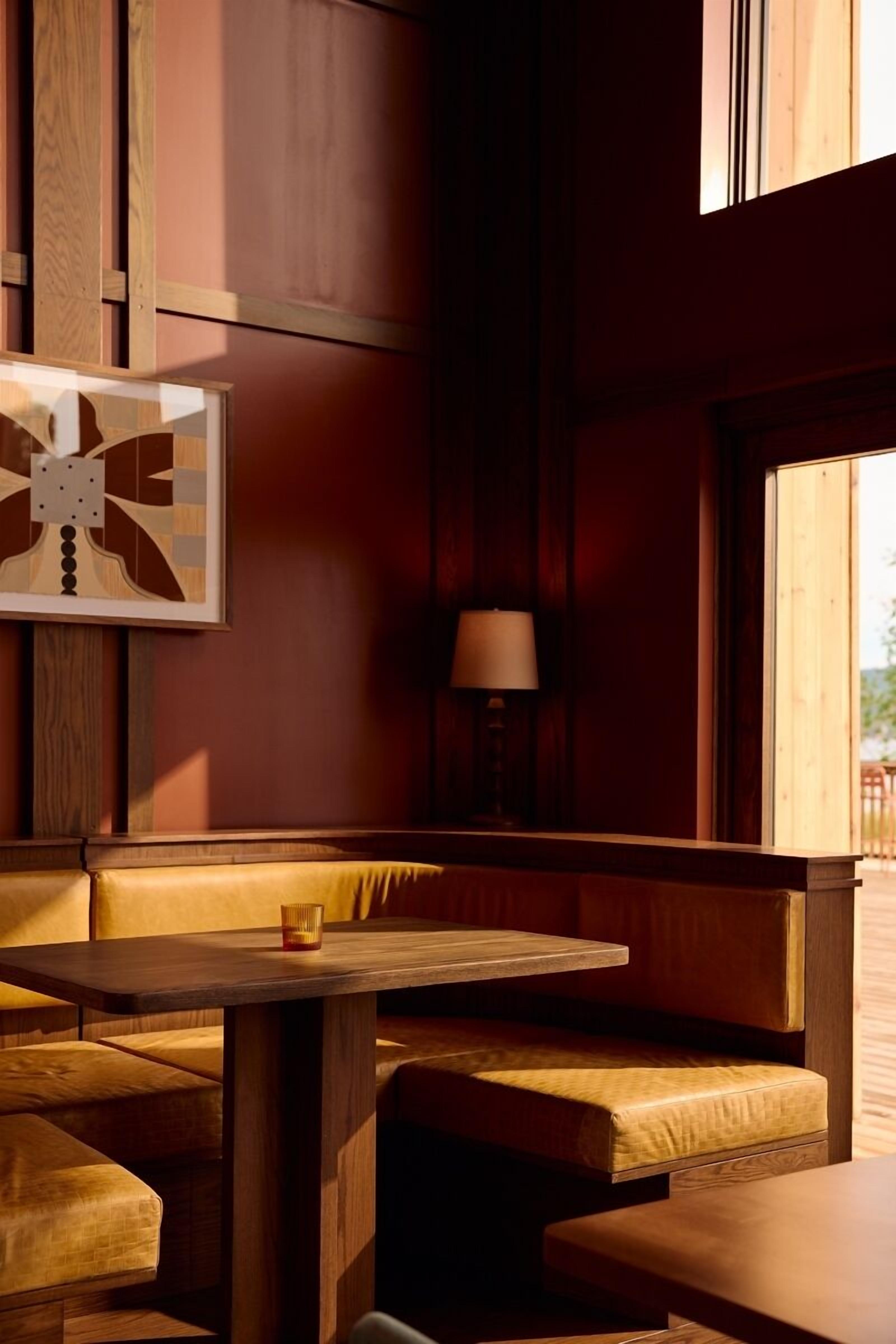 Ein gemütlicher Sitzbereich mit Holzmöbeln, einem Tisch, einer Lampe und einem gerahmten Kunstwerk an der Wand.