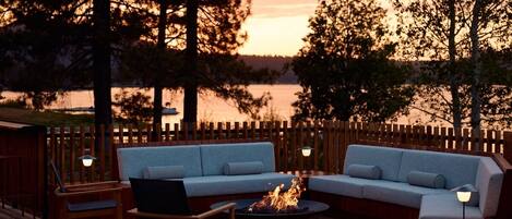 Eine Terrasse mit einer Couch, Stühlen und einem Feuerkorb.