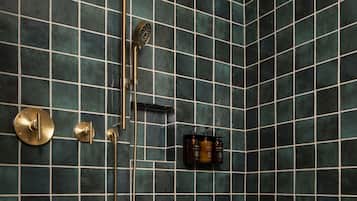 Un baño con ducha, un banco de madera y un estante con artículos de aseo.