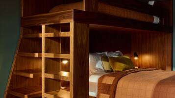 A bunk bed with a wooden ladder and shelves, a bedside table with a lamp, and a carpeted floor.