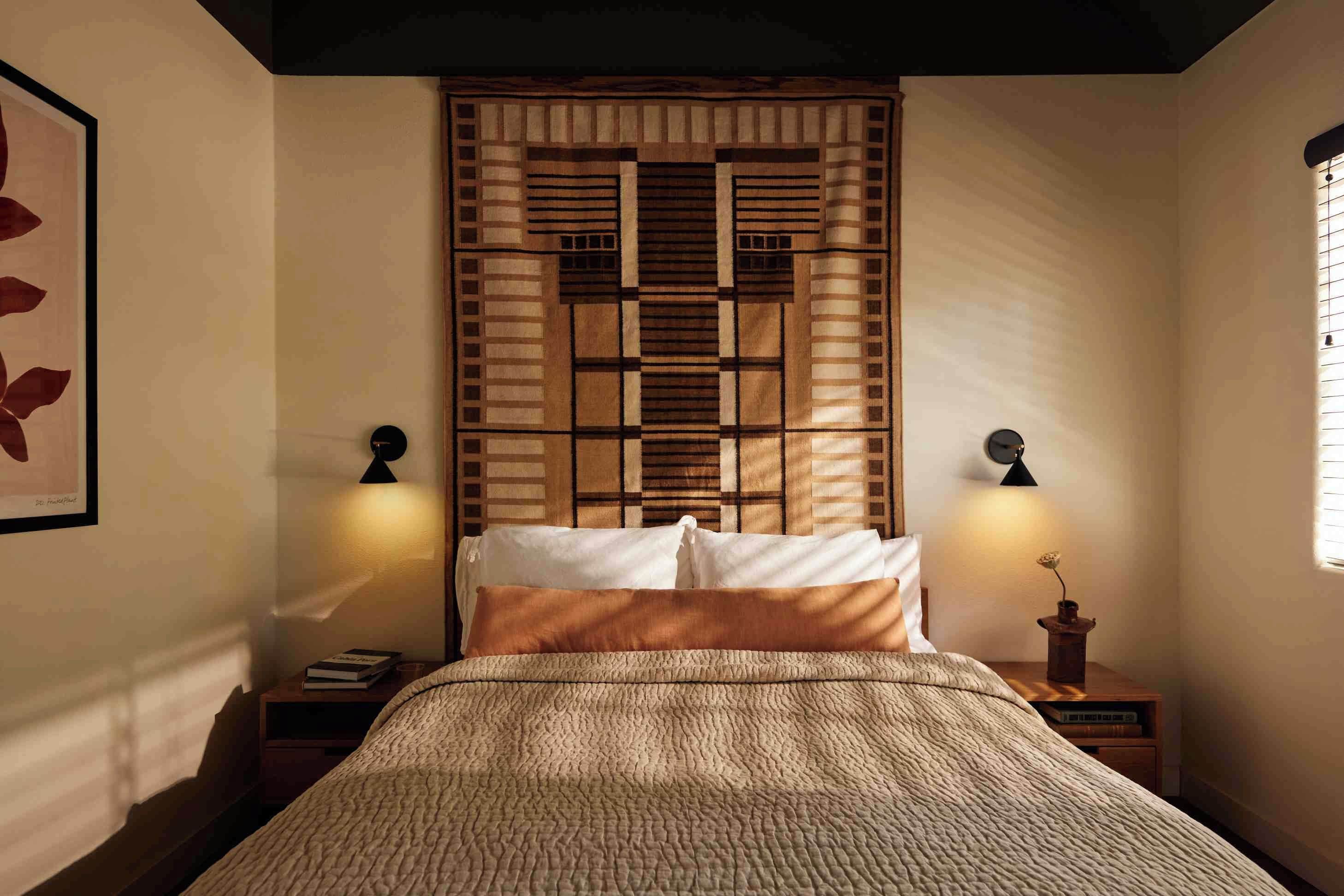 A bedroom with a bed, two bedside tables, a wall-mounted clock, and a decorative panel above the bed.