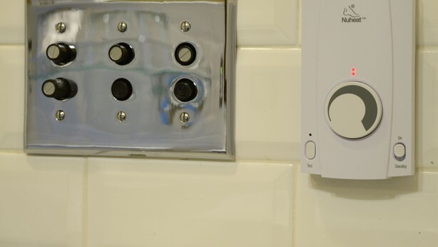 A Nuheat™ wall-mounted hand dryer with a test and standby button, and a metallic vent cover with multiple outlets. - New Sheridan Hotel (Telluride)