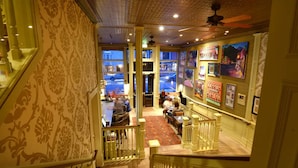 A hotel lobby with ornate wallpaper, a staircase, and a view of the street outside. - New Sheridan Hotel (Telluride)