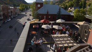 A town square with outdoor seating, a clock tower, and a mountain backdrop. - New Sheridan Hotel (Telluride)