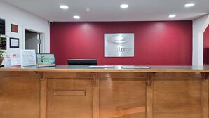 A reception desk with a red wall, a sign for Econ Lodge, and a security camera.