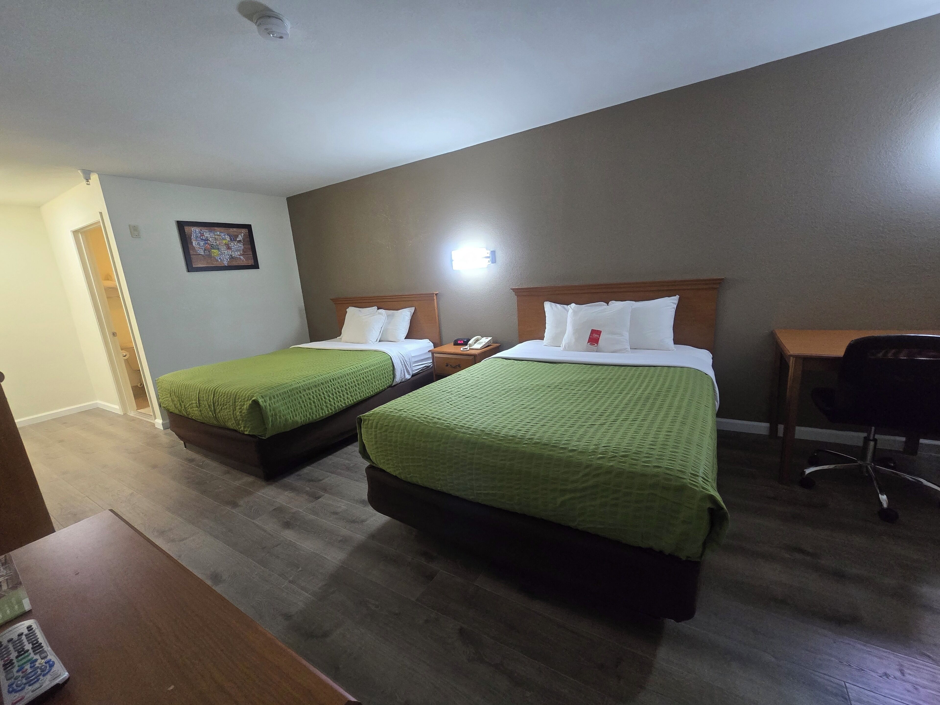 Ett hotellrum med två sängar, ett skrivbord och en stol.