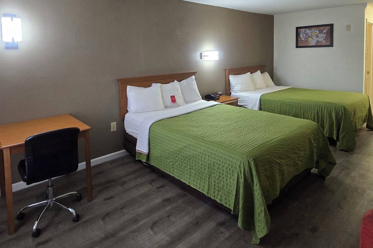 Une chambre d’hôtel avec deux lits simples, un bureau et une chaise.