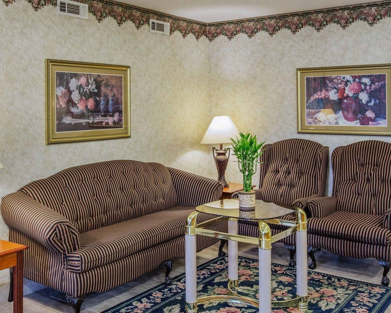 A room with striped sofas, a glass coffee table, and two wall-mounted lamps.
