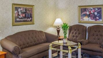 A room with striped sofas, a glass coffee table, and two wall-mounted lamps.