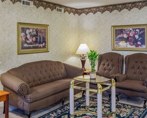 A room with striped sofas, a glass coffee table, and two wall-mounted lamps. - Econo Lodge Villa Rica (Villa Rica)