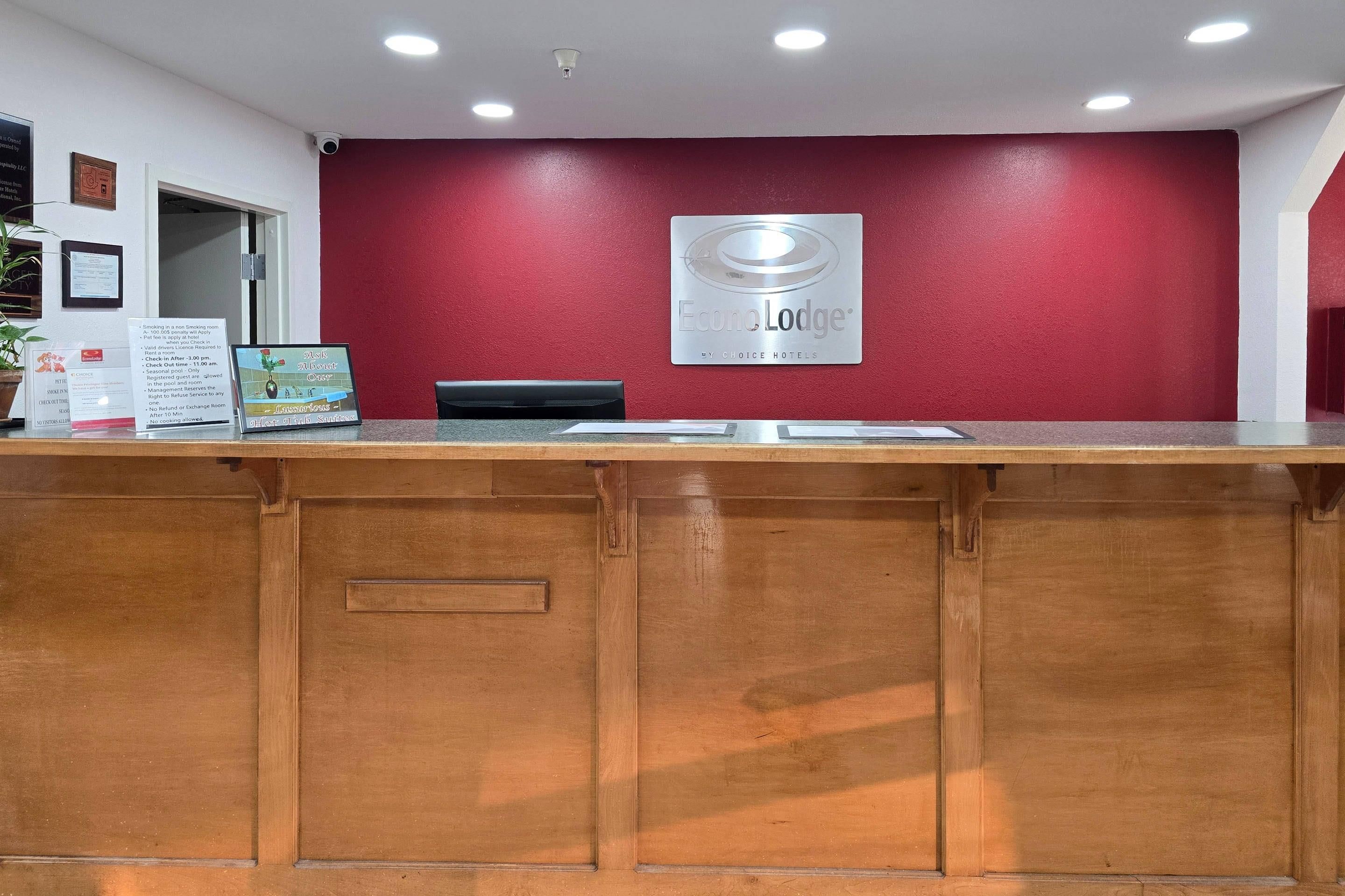 A reception desk with a red wall, a framed sign, and a security camera.