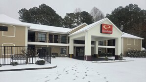 A hotel with a central entrance, multiple balconies, and a snow-covered ground.