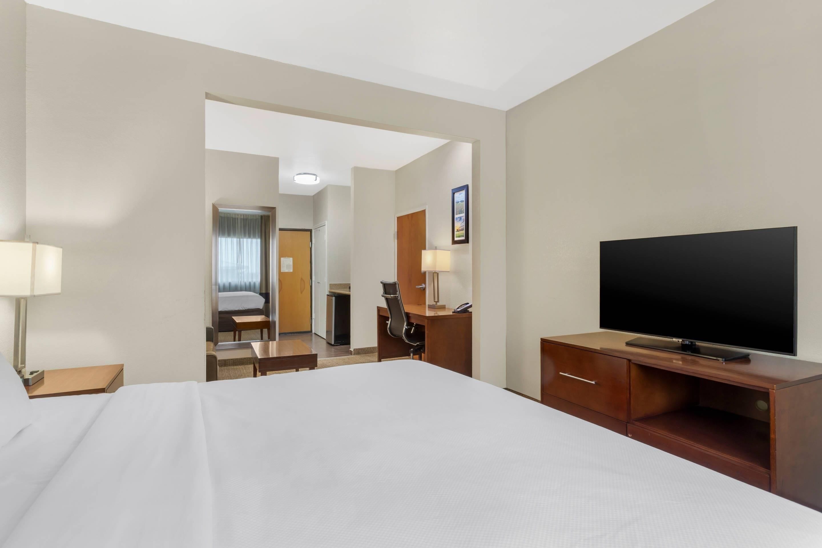 Une chambre d’hôtel avec un lit, une télévision, un bureau et une chaise.