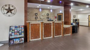 A reception desk with a Texas star sign, a wooden counter, and a wall-mounted clock. - Comfort Suites Brenham (Brenham)