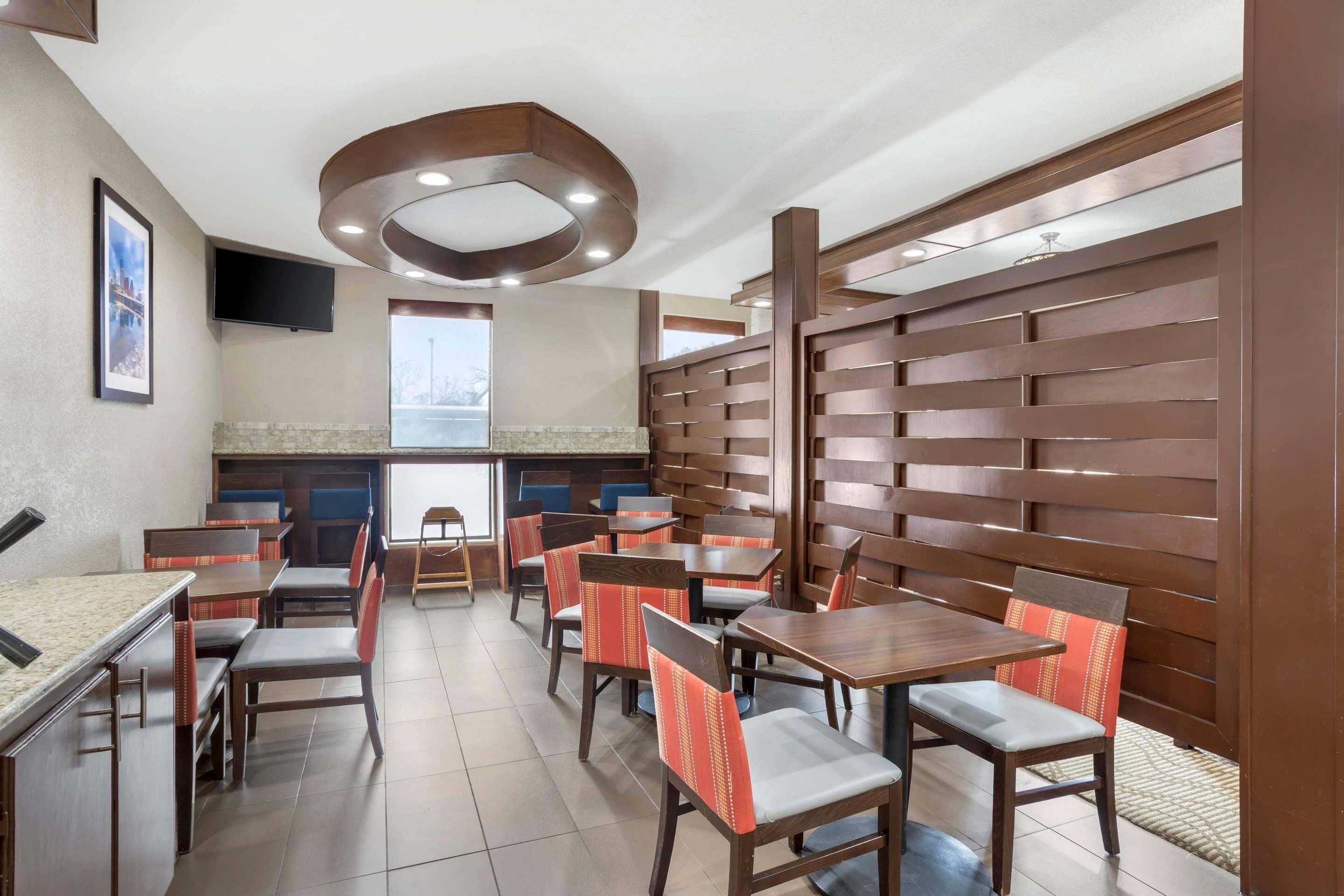 A restaurant with wooden panel walls, multiple tables and chairs, and a television mounted on the wall.