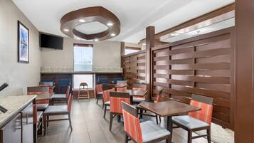 A restaurant with wooden panel walls, multiple tables and chairs, and a television mounted on the wall.