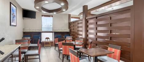 A restaurant with wooden panel walls, multiple tables and chairs, and a television mounted on the wall.