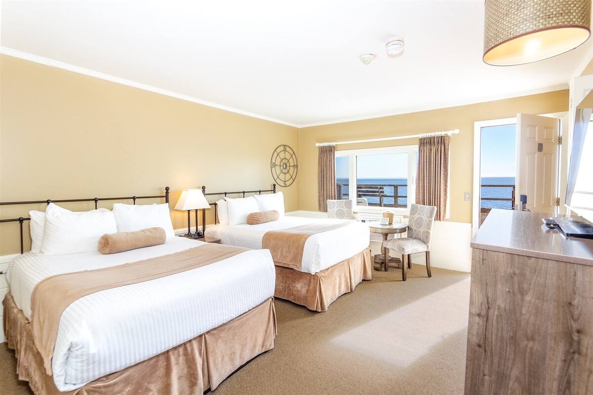 Une chambre d’hôtel avec deux lits, un bureau, une chaise et une vue sur la mer.