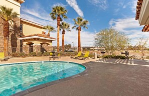 A swimming pool with lounge chairs and palm trees.