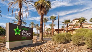 Señal de Extended Stay America Suites con paisaje desértico y palmeras de fondo.