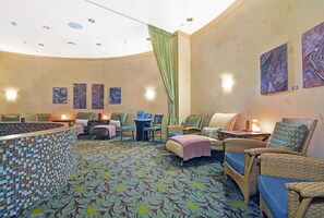 Un cuarto de spa con techo curvo, piso estampado y varias zonas de estar con sillas y una mesa.