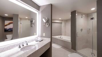 A modern bathroom with a large mirror, two sinks, a bathtub, and a glass-enclosed shower.