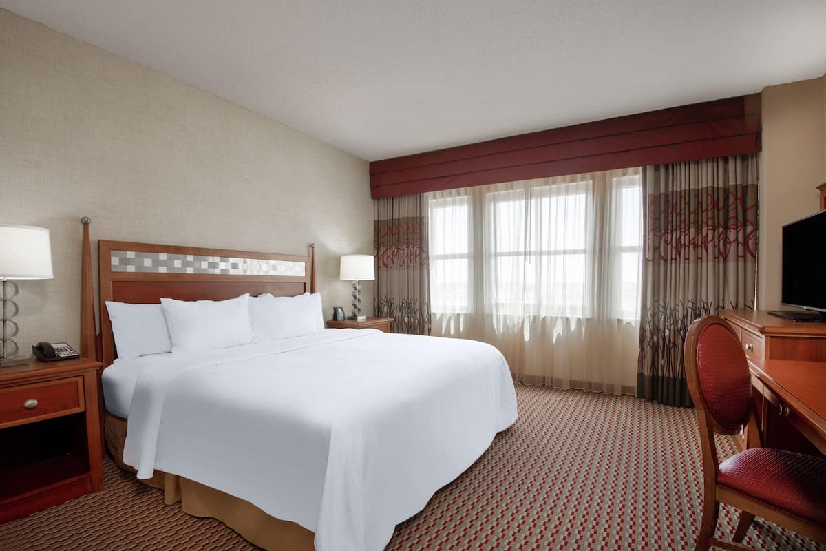 Een hotelkamer met een groot bed, een bureau, een stoel, een televisie en een telefoon op het nachtkastje.