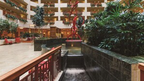 A spacious atrium with multiple floors, a central water feature, and lush greenery.