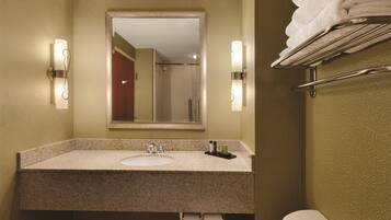 A bathroom with a sink, mirror, towel rack, and a toilet.