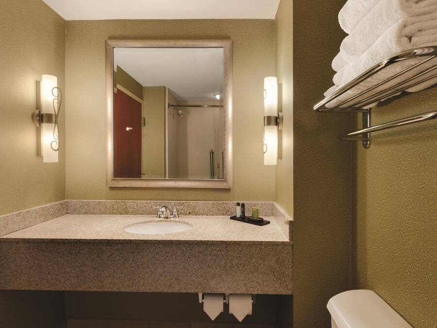 A bathroom with a sink, mirror, towel rack, and a toilet.