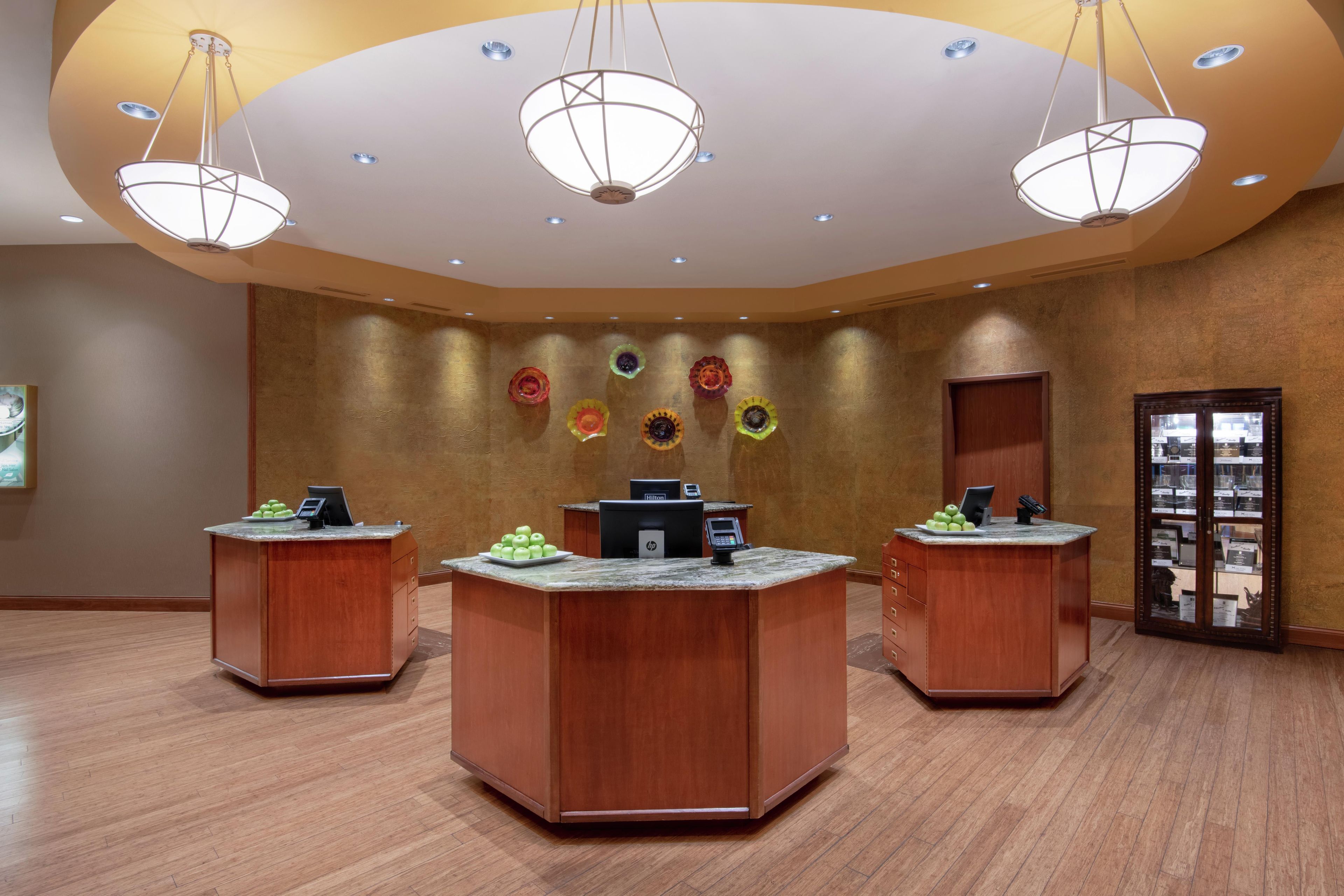 A hotel reception area with three wooden reception desks, each equipped with a computer and a phone.