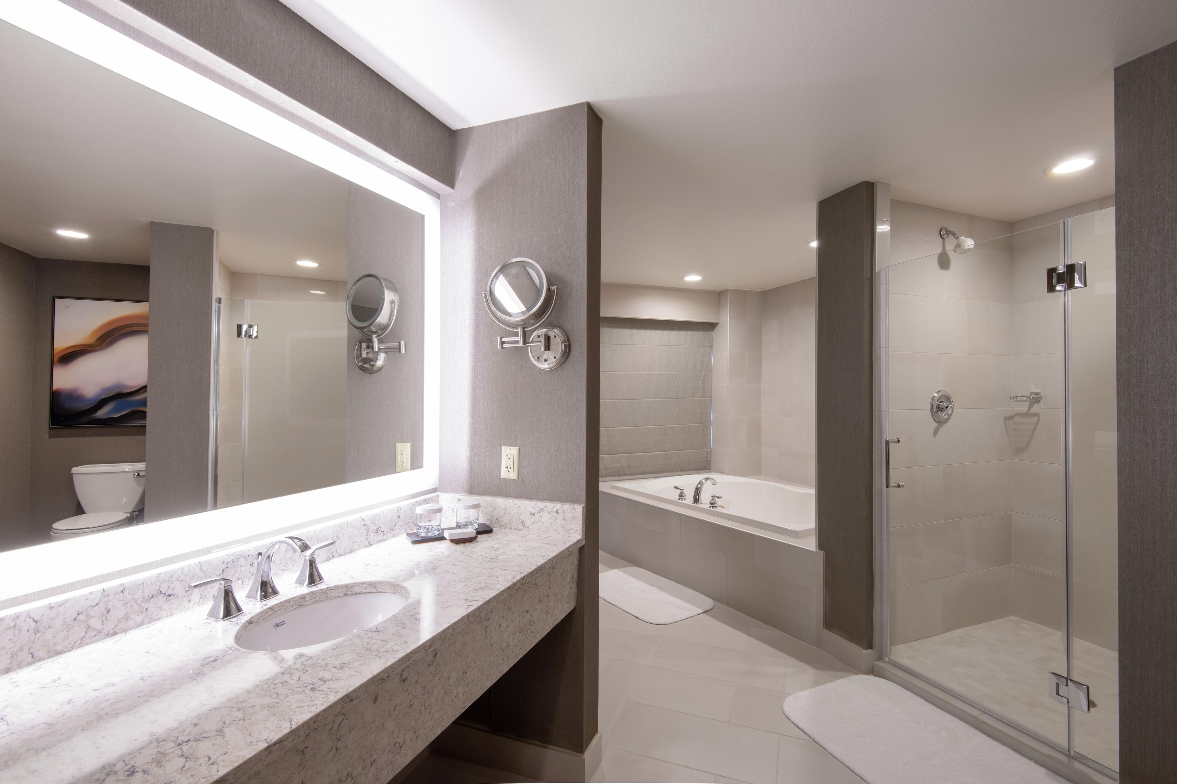 Une salle de bain moderne avec un grand miroir, deux lavabos, une douche et une baignoire.