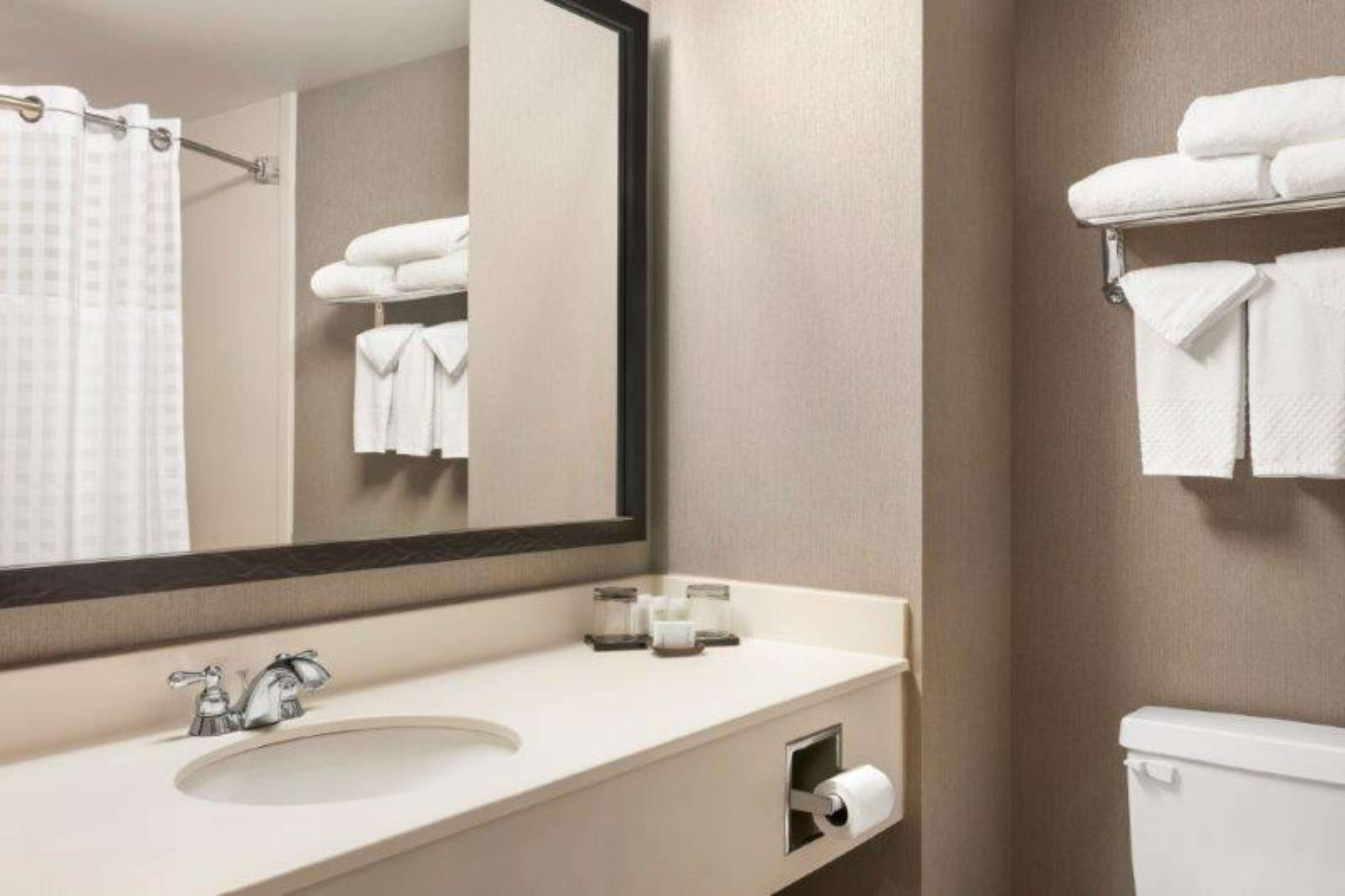 A bathroom with a sink, mirror, towel rack, and toilet.
