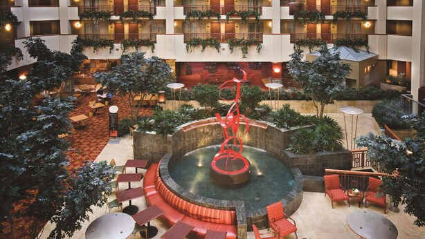A hotel atrium with a central fountain, multiple seating areas, and balconies with plants.