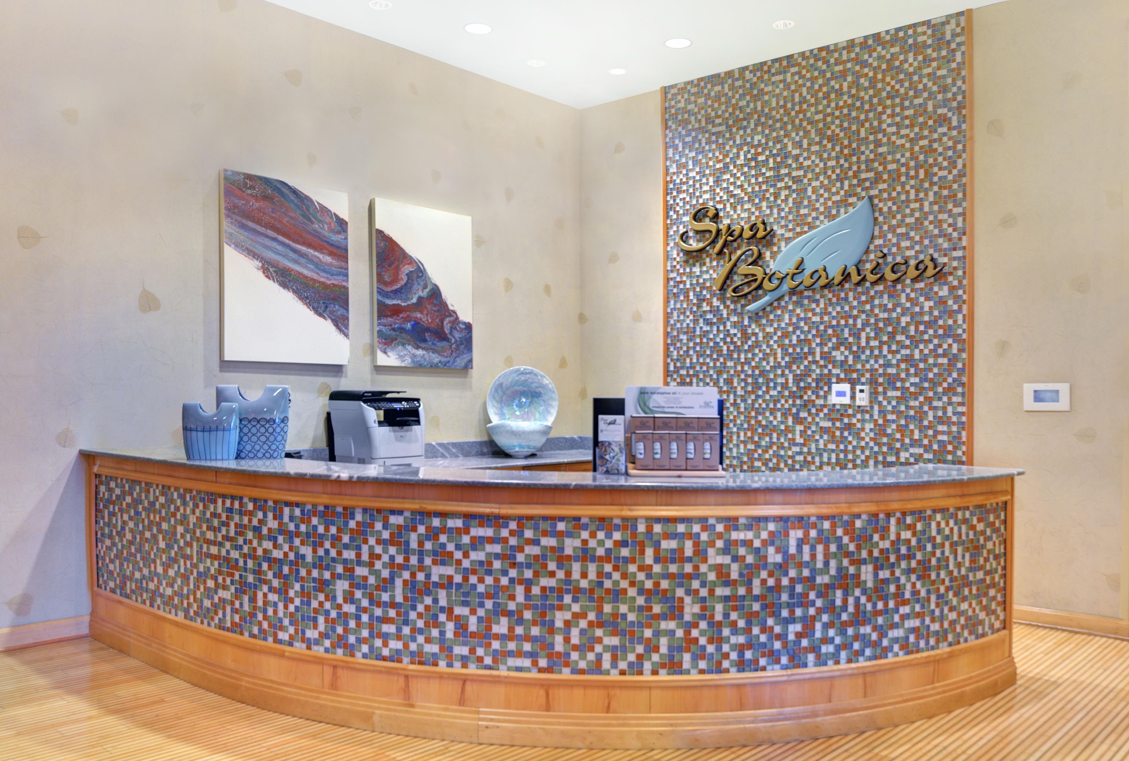 A reception desk with a mosaic tile design, a coffee machine, a glass bowl, and two framed artworks on the wall.