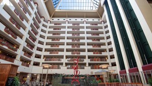 A multi-level atrium with a central fountain, balconies with plants, and a high ceiling with skylights.
