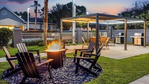 Eine Terrasse im Freien mit Adirondack-Stühlen, einer Feuerstelle und einem überdachten Grillbereich.