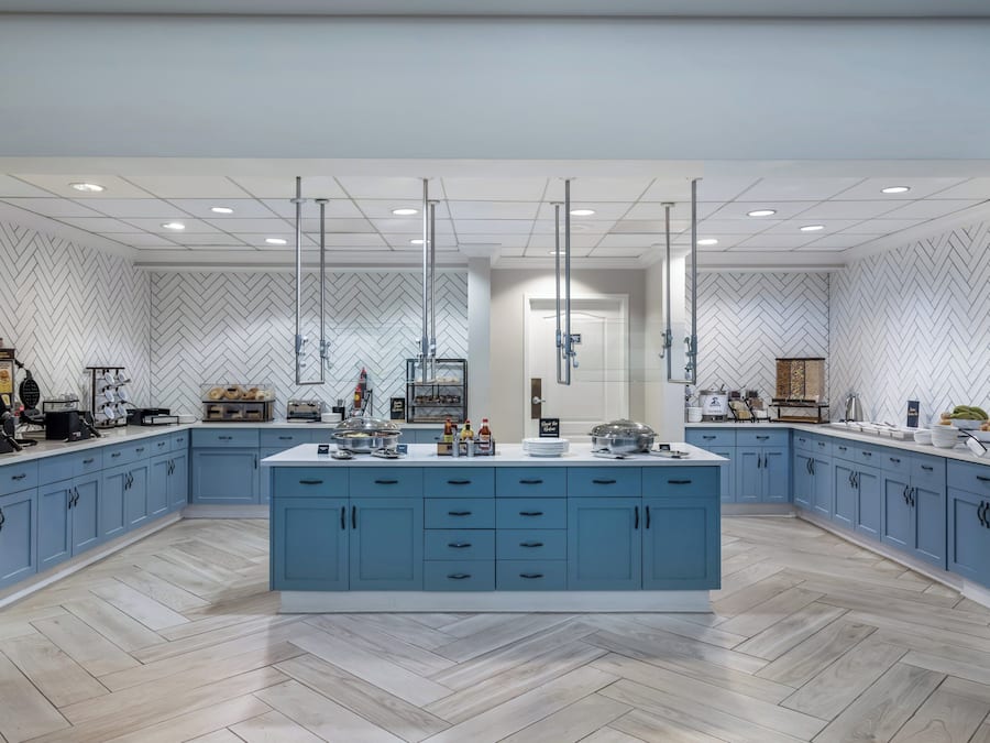 A spacious kitchen with a central island, blue cabinets, and a herringbone-patterned backsplash.