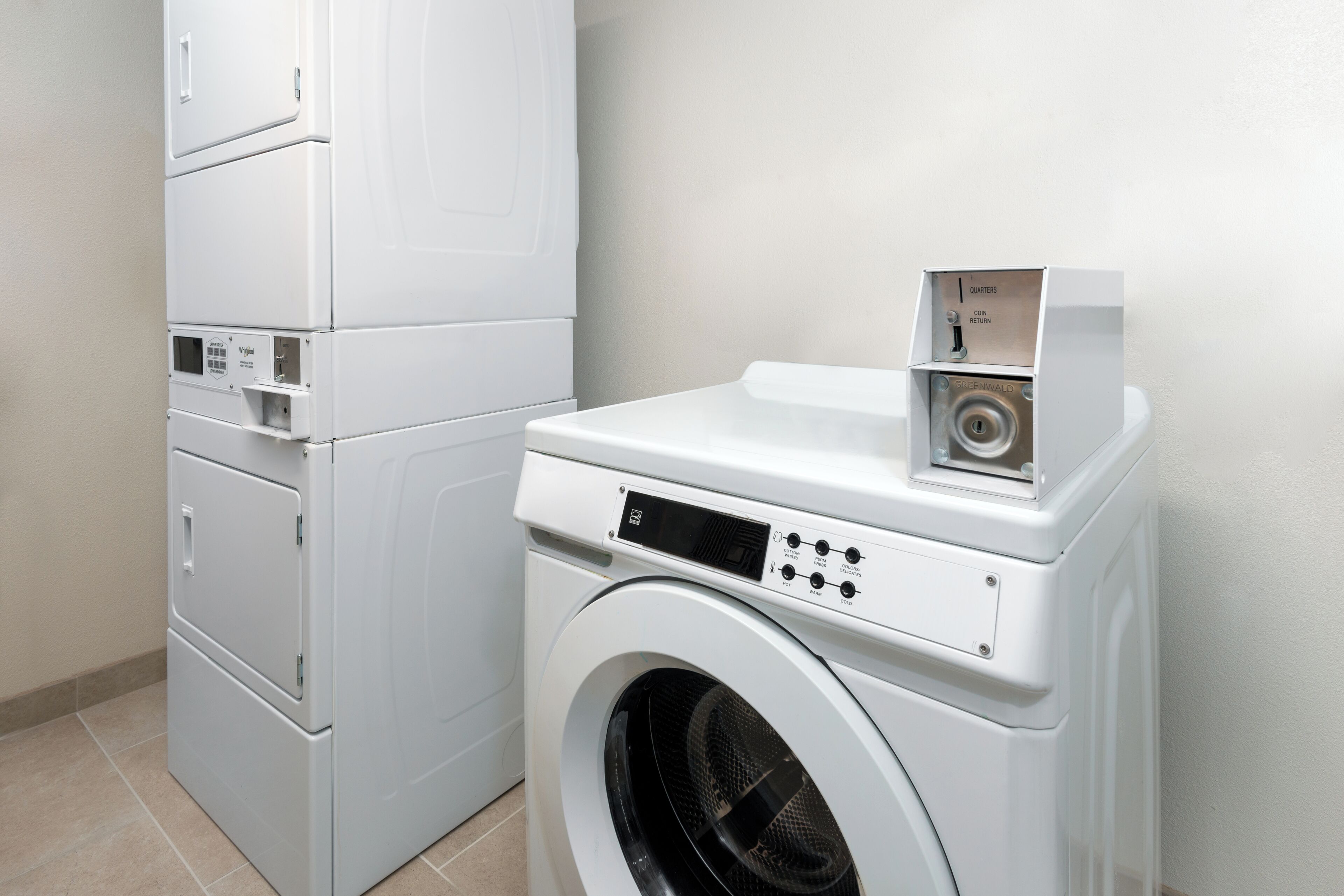 A compact laundry area with a front-loading washing machine and stacked dryers.