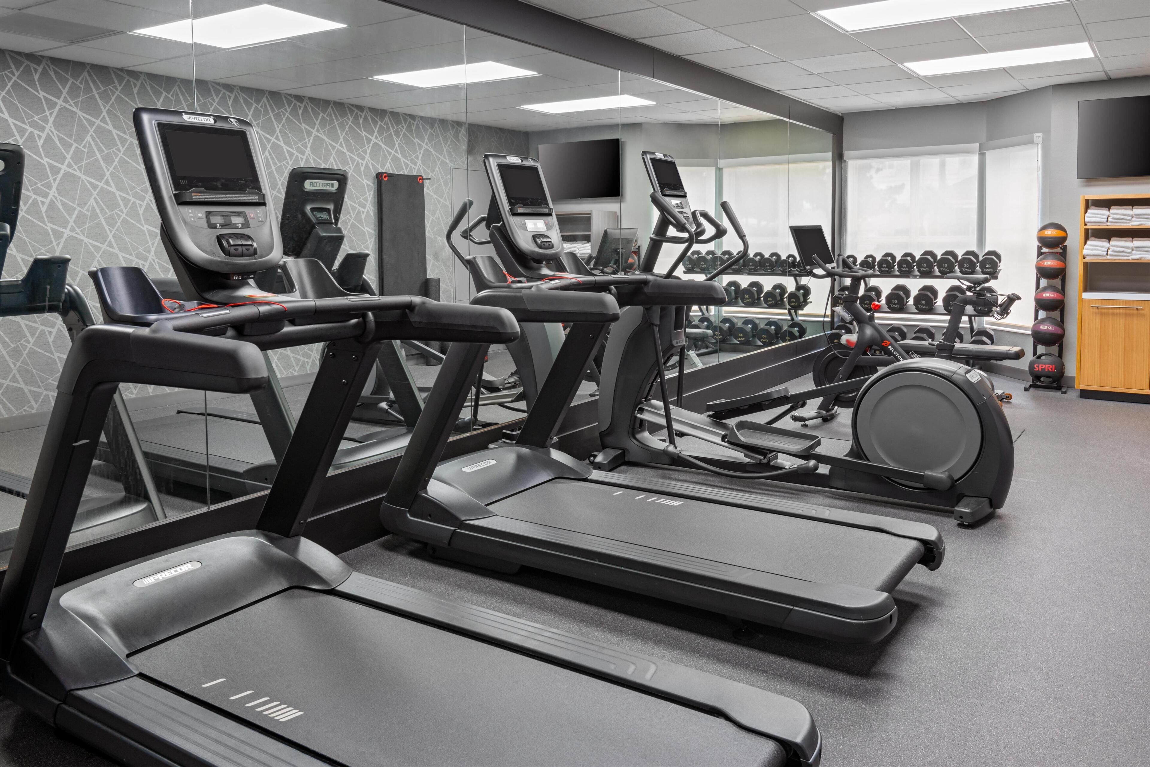A gym with treadmills, ellipticals, and a wall-mounted TV.