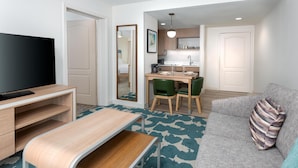 A compact living space with a TV, a dining table, a sofa, and a kitchenette.