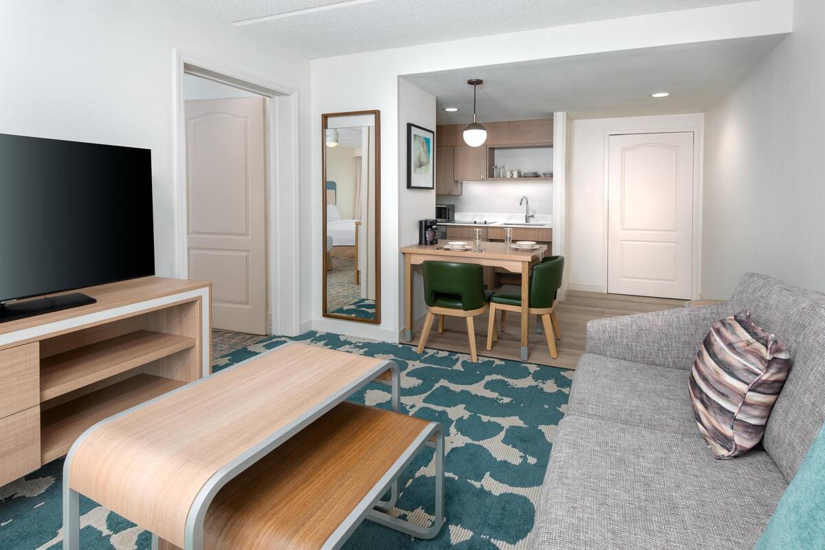 Un espace de vie compact comprenant un téléviseur, une table à manger, un canapé et une kitchenette.
