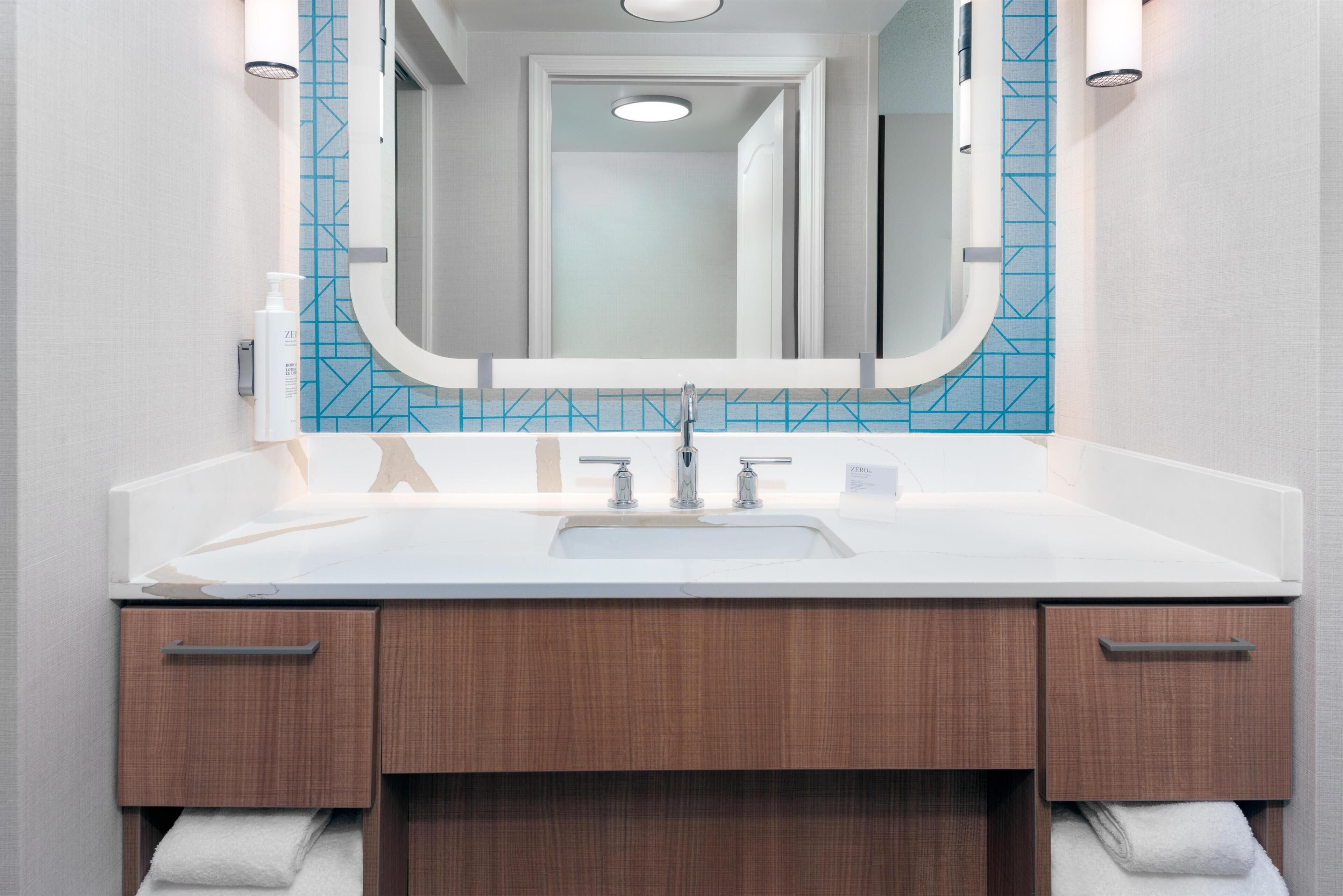 A bathroom with a white sink, a mirror, and wooden cabinets.