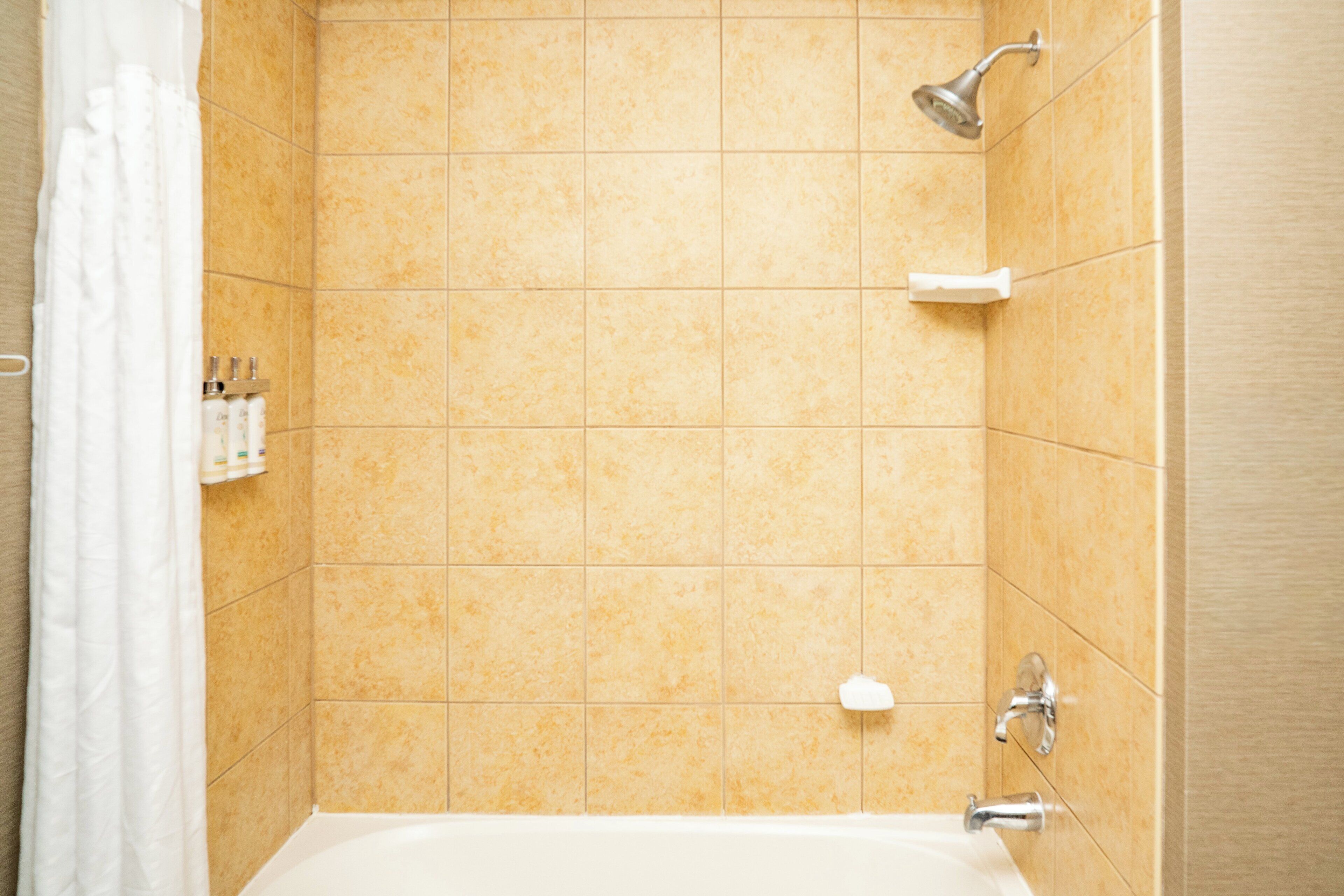 A bathroom with a bathtub, shower, and tiled walls.
